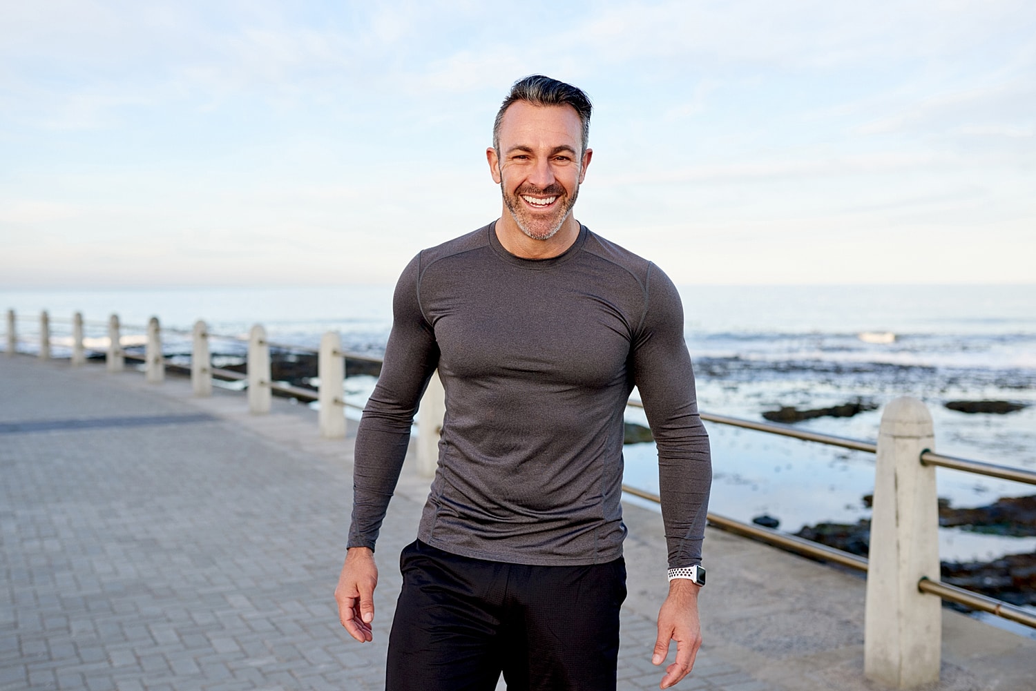 Pittsburgh Male Facelift model smiling by the seaside in athletic wear.