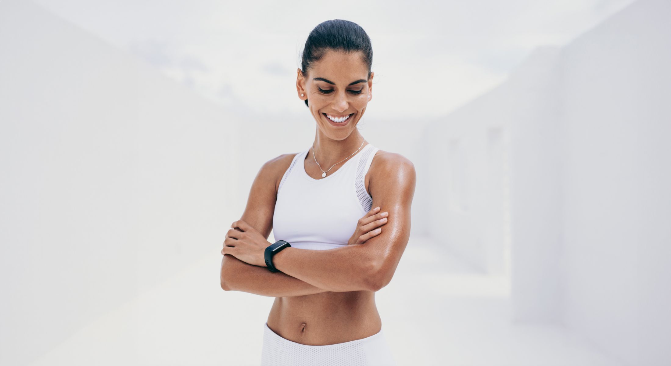 Smiling woman in athletic wear, arms crossed.