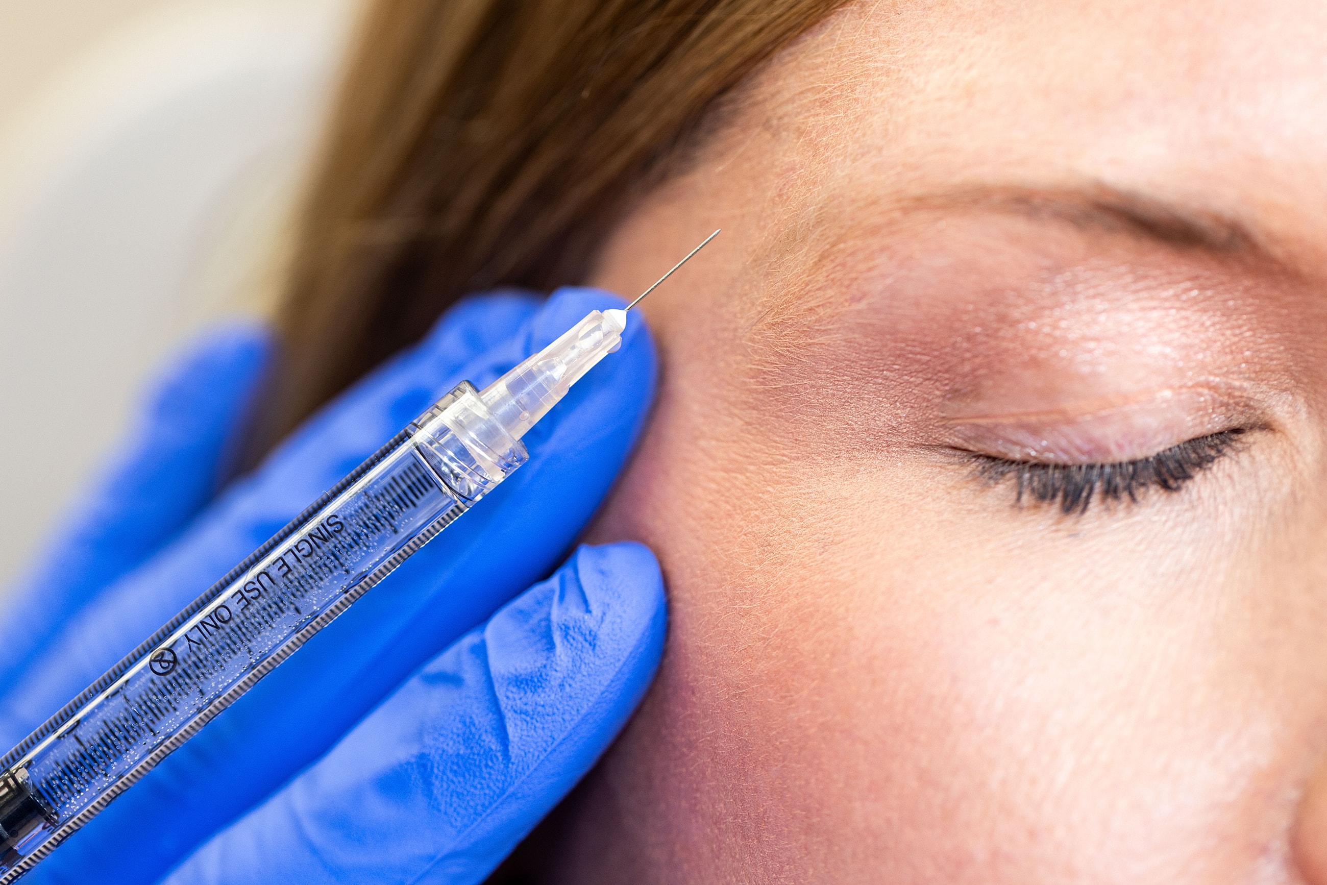 Injecting treatment near closed eye with syringe.