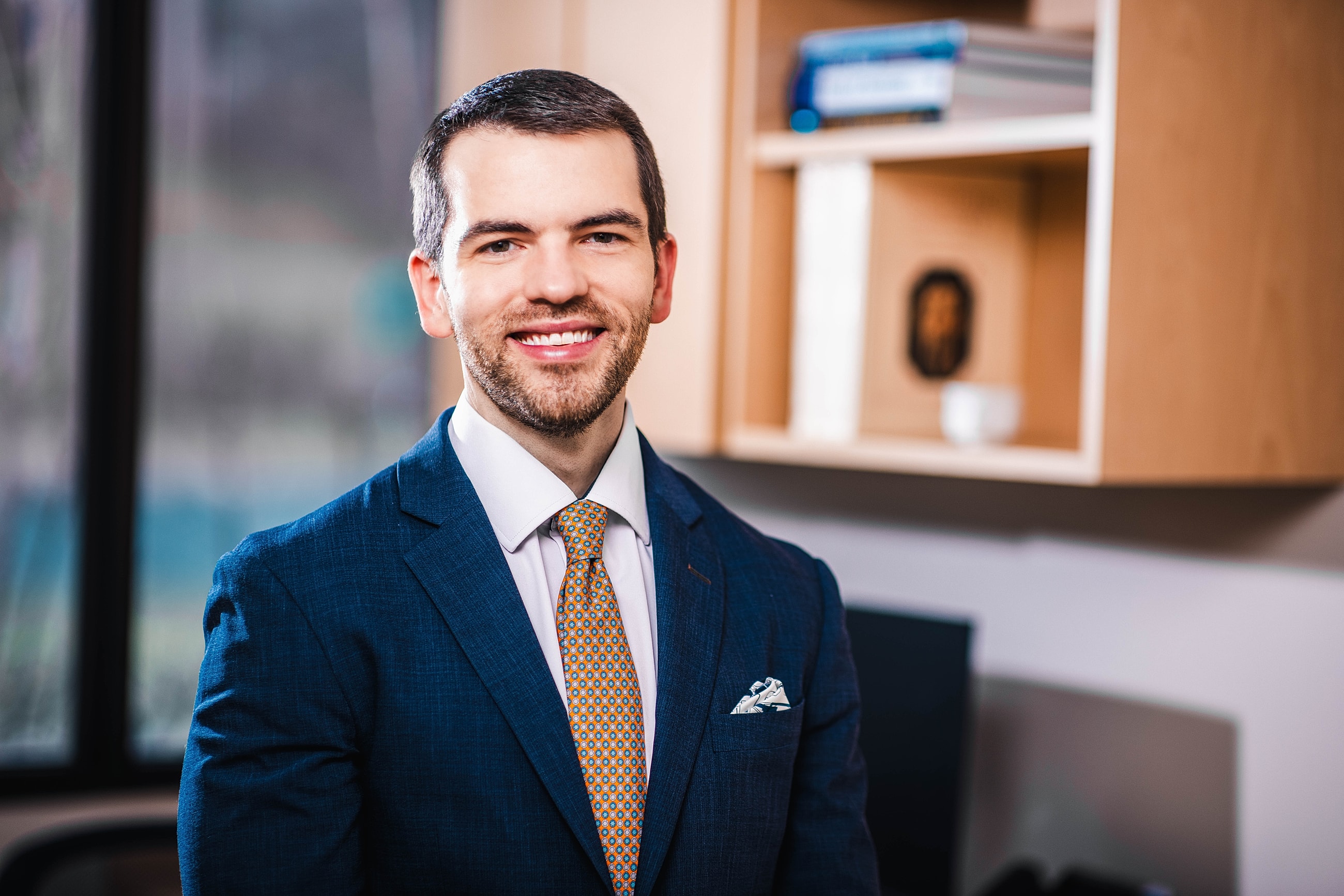 Smiling man in a suit, office backdrop.